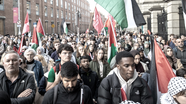Large crowd in front of Dáil Éireann holding Palestine flags and People Before Profit flags wearing keffiyahs in solidarity with Palestine. Original image found on IrishTimes.com